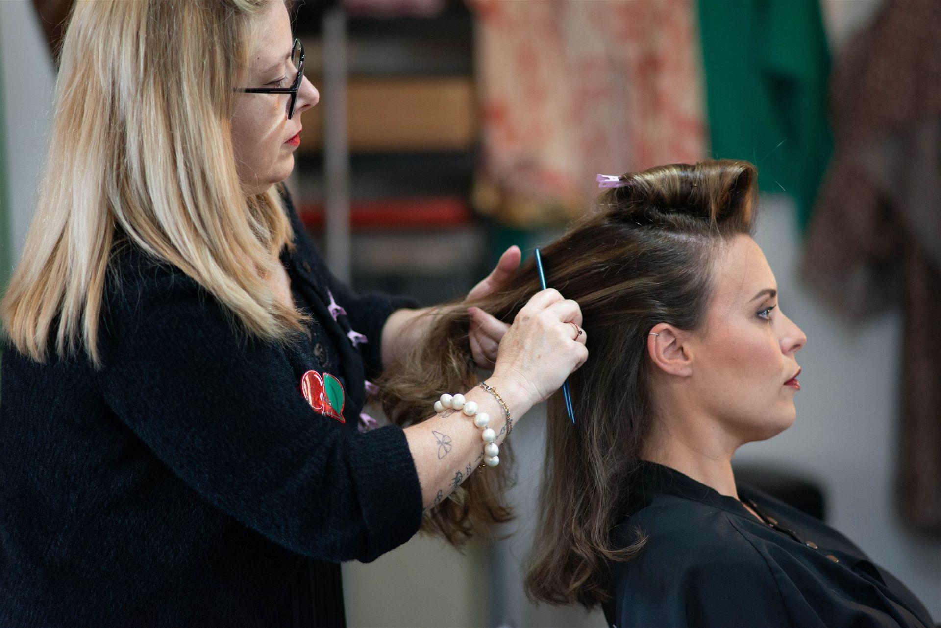 Mains d'Annabel travaillent le chignon d'Amandine avec des épingles roses — coiffure mariage Perpignan