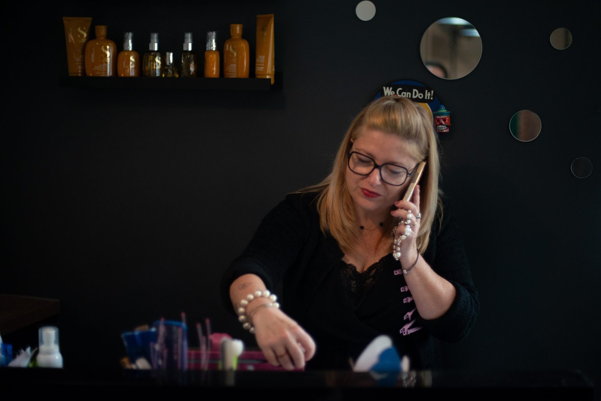 Coiffeuse Annabel au téléphone derrière le comptoir de son salon de coiffure à Perpignan