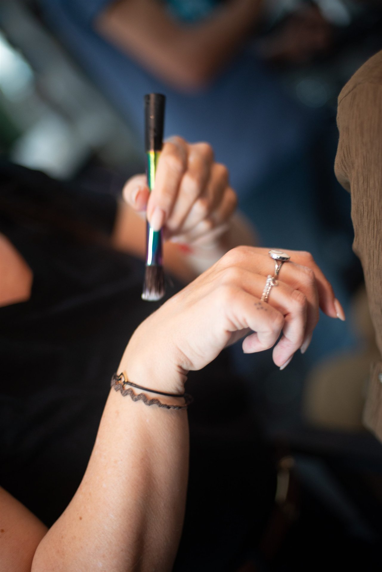 Détail des mains de Magali tenant un pinceau de maquillage avec une bague — shooting mariage Perpignan