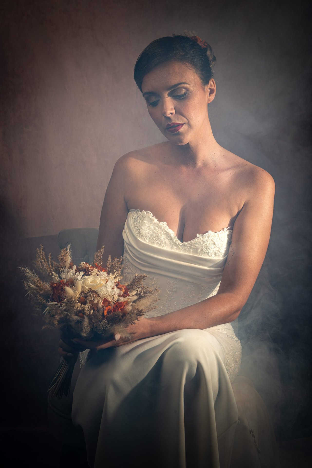 Portrait mariée avec bouquet de fleurs séchées terracotta sur fond texturé brun — shooting mariage Perpignan